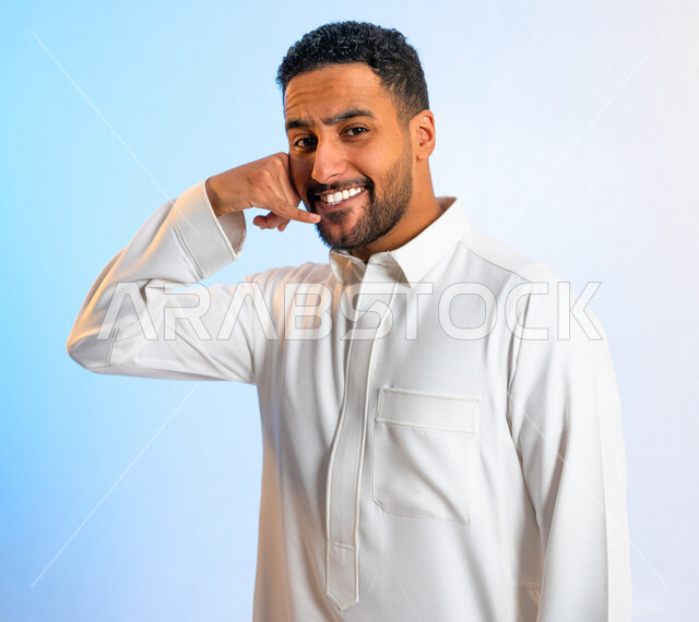 بورتريه لرجل عربي سعودي خليجي مبتسم بايماءات يد تدل على اجراء مكالمة هاتفية  ، انتظار مكالمة ، اشارة للاتصال ،استخدام الميكروفون