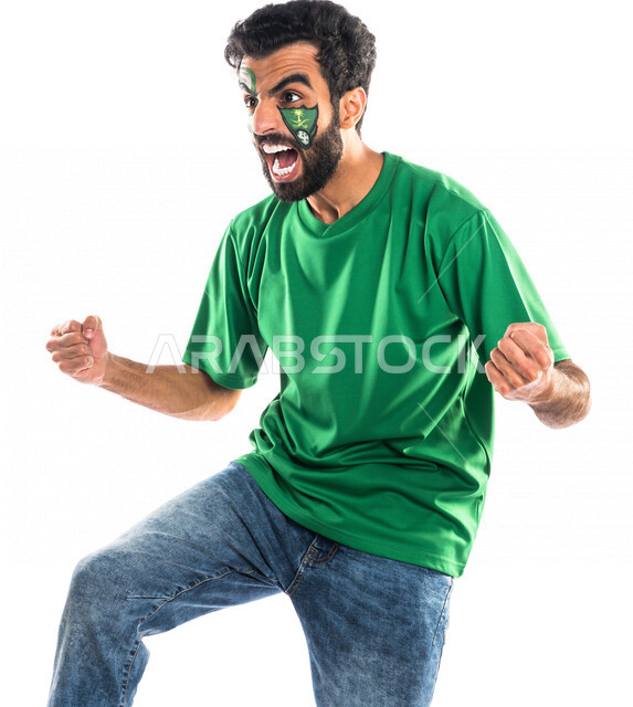 بورتريه لشاب عربي خليجي سعودي يرتدي تيشرت نادي الأهلي السعودي، تشجيع فريق الأهلي السعودي لكرة قدم، متابعة مباراة كرة قدم، شاب يرسم على وجهه شعار نادي الأهلي السعودي، إيماءات وجه ويدين تدل على السعادة والحماس والشغف بالفوز، خلفية بيضاء