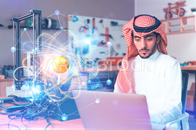 شاب عربي خليجي سعودي يستخدم الحاسوب المحمول ، التعليم الالكتروني ، العمل عن بعد ، دراسات وابحاث علمية ، دراسة الفيزياء والكيمياء ،خلفية للذرة بتقنية الهولوجرام 