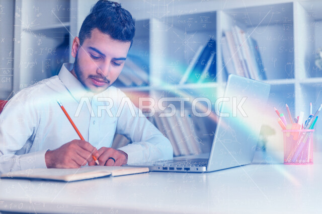 A Saudi Arabian Gulf student sitting in front of a laptop and taking notes on the notebook, following up on lessons and lectures remotely, e-learning, scientific research, background for a set of mathematical laws