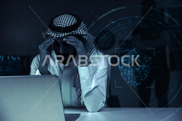 رجل عربي خليجي سعودي يجلس امام الحاسوب المحمول بايماءات تدل على الخسارة ،التعرض لسرقة كلمات المرور والبيانات الشخصية ، اختراق النظام والبيانات، جرائم الكترونية ،الهجمات الالكترونية ، خلفية لقفل بتقنية الهولوجرام