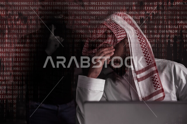 A Saudi Arabian Gulf man sitting in front of the laptop with gestures indicating loss, theft of passwords and personal data, penetration of the system and data, cyber crimes, electronic attacks, background of programming language and a man hacker