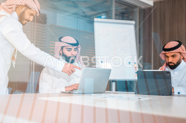 مجموعة من الموظفين الخليجيين السعوديين في اجتماع داخل شركة سعودية ، استخدام الحاسوب المحمول لمتابعة البورصة ،تحليل بيانات المبيعات ومخطط الرسم البياني للنمو الاقتصادي. استراتيجية المال والاعمال ، التسويق الرقمي، خلفية للمخطط البياني