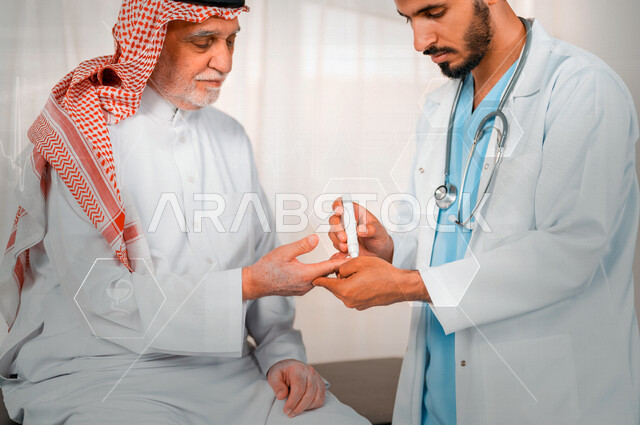 طبيب عربي خليجي سعودي يقوم بفحص مريض كبير بالسن يعاني من داء السكري، مشاكل ارتفاع وانخفاض السكر في الدم، جهاز قياس السكر في الدم خاص لمرضى السكري، حالة مرضية، مفهوم الطب والرعاية الطبية، مهن ووظائف طبية، إستخدام تقنية الهولوجرام ثلاثية الأبعاد