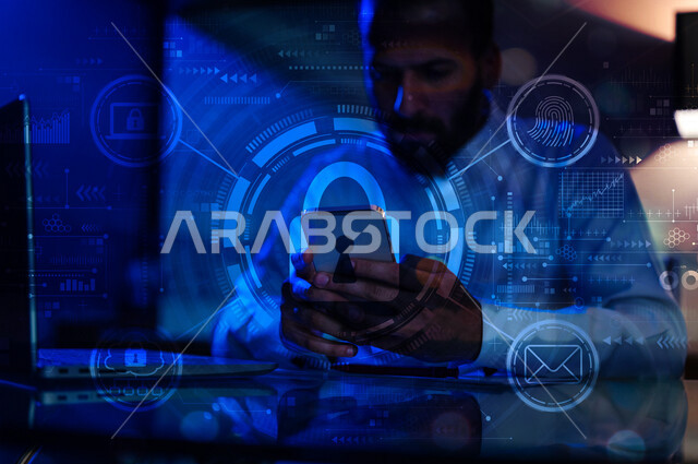 صورة مقربة ليد رجل عربي خليجي سعودي يستخدم الهاتف المحمول ، أيقونة قفل الأمان مضيئة داخل شبكة عنكبوتية محاطة بمجموعة أيقونات خاصة بالانترنت بتقنية الهولوجرام ثلاثية الأبعاد ، الحفاظ على البيانات الشخصية والدخول الآمن، الحماية والأمان
