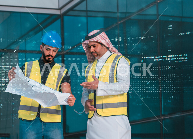 Two Saudi and Gulf architects discuss a blueprint for a construction project, wearing a protective work jacket, auditing work, supervising and discussing projects under construction, the concept of architecture, engineering project management, engineering