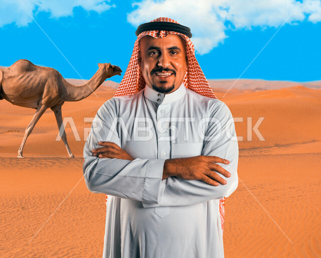 A picture of a Saudi Arabian Gulf man looking at the camera with crossed hands against a background of a camel walking in the desert of Saudi Arabia, sand dunes, a road trip in the desert areas of Saudi Arabia, tourism in Saudi Arabia, desert nature in Sa