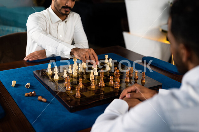 صورة مقربة لشابان عربيان سعوديان خليجيان يلعبان لعبة الشطرنج, مفهوم التركيز و التحدي, التخطيط والتفكير, لعبة رقمية استراتيجية على رقعة الشطرنج, أنشطه ترفيهيه, قضاء وقت ممتع مع الأصدقاء, تسليه وترفيه
