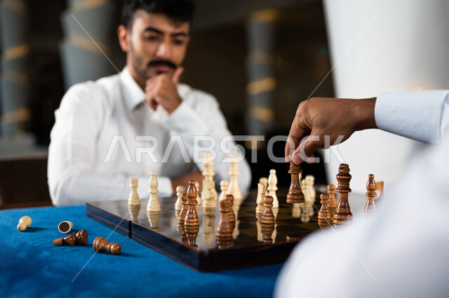 صورة مقربة لشابان عربيان سعوديان خليجيان يلعبان لعبة الشطرنج, مفهوم التركيز و التحدي, التخطيط والتفكير, لعبة رقمية استراتيجية على رقعة الشطرنج, أنشطه ترفيهيه, قضاء وقت ممتع مع الأصدقاء, تسليه وترفيه