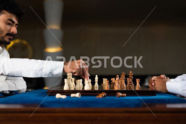 صورة مقربة لشابان عربيان سعوديان خليجيان يلعبان لعبة الشطرنج, مفهوم التركيز و التحدي, التخطيط والتفكير, لعبة رقمية استراتيجية على رقعة الشطرنج, أنشطه ترفيهيه, قضاء وقت ممتع مع الأصدقاء, تسليه وترفيه