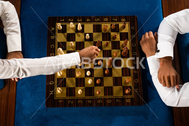 صورة مقربة لشابان عربيان سعوديان خليجيان يلعبان لعبة الشطرنج, مفهوم التركيز و التحدي, التخطيط والتفكير, لعبة رقمية استراتيجية على رقعة الشطرنج, أنشطه ترفيهيه, قضاء وقت ممتع مع الأصدقاء, تسليه وترفيه