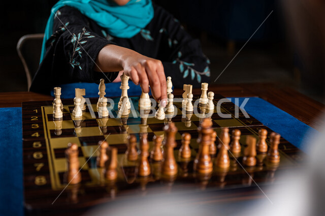 صورة مقربة لإمرأه عربيه سعوديه خليجيه تلعب لعبة الشطرنج, مفهوم التركيز و التحدي, التخطيط والتفكير, لعبة رقمية استراتيجية على رقعة الشطرنج, أنشطه ترفيهيه, قضاء وقت ممتع, تسليه وترفيه
