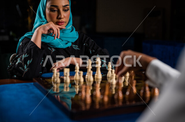 صورة مقربة لإمرأه وشاب عربيان سعوديان خليجيان يلعبان لعبة الشطرنج, مفهوم التركيز و التحدي, التخطيط والتفكير, لعبة رقمية استراتيجية على رقعة الشطرنج, أنشطه ترفيهيه, قضاء وقت ممتع مع الأصدقاء, تسليه وترفيه