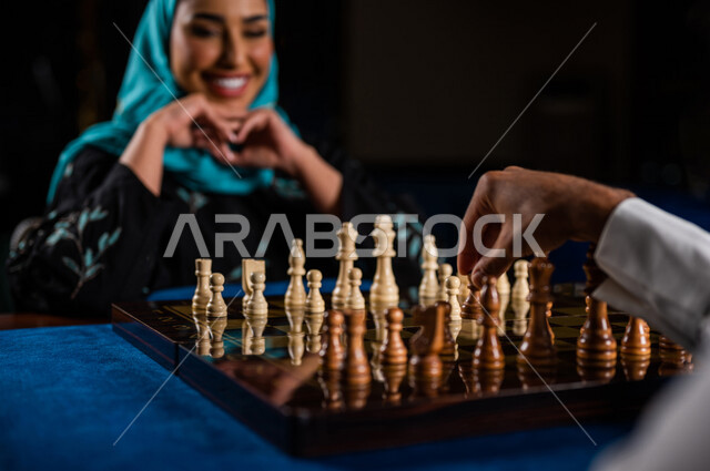 صورة مقربة لإمرأه وشاب عربيان سعوديان خليجيان يلعبان لعبة الشطرنج, مفهوم التركيز و التحدي, التخطيط والتفكير, لعبة رقمية استراتيجية على رقعة الشطرنج, أنشطه ترفيهيه, قضاء وقت ممتع مع الأصدقاء, تسليه وترفيه