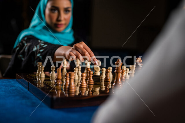 صورة مقربة لإمرأه وشاب عربيان سعوديان خليجيان يلعبان لعبة الشطرنج, مفهوم التركيز و التحدي, التخطيط والتفكير, لعبة رقمية استراتيجية على رقعة الشطرنج, أنشطه ترفيهيه, قضاء وقت ممتع مع الأصدقاء, تسليه وترفيه