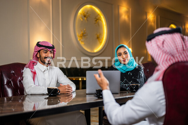 زملاء عمل عرب سعوديون خليجيون مجتمعون في المقهى, حوار ونقاش عمل خارج الشركه, انجاز مهام العمل عبر جهاز الحاسوب, إدارة الأعمال عن بعد, توزيع مهام العمل بين الزملاء,  الإستمتاع بشرب القهوه في متجر القهوه, مقاهي في المملكه العربيه السعوديه