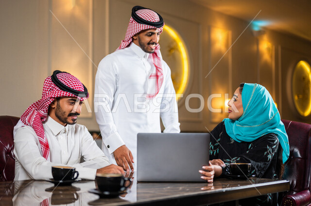 زملاء عمل عرب سعوديون خليجيون مجتمعون في المقهى, حوار ونقاش عمل خارج الشركه, انجاز مهام العمل عبر جهاز الحاسوب, إدارة الأعمال عن بعد, توزيع مهام العمل بين الزملاء,  الإستمتاع بشرب القهوه في متجر القهوه, مقاهي في المملكه العربيه السعوديه