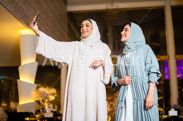 سيدتان عربيتان خليجيتان سعوديتان صديقتان مبتسمتان تقومان بالتقاط صورة سلفي تذكارية عبر الهاتف المحمول ، سياحة و استجمام ، صداقات و تعارف ، علاقات إجتماعية ، قضاء أوقات ممتعة