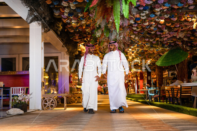 رجلان عربيان خليجيان سعوديان صديقان مبتسمان يسيران معاً في نزهة ممتعة لإحدى الأماكن الترفيهية ، صداقات و تعارف ، علاقات إجتماعية ، كوفي شوب ، قضاء أوقات ممتعة