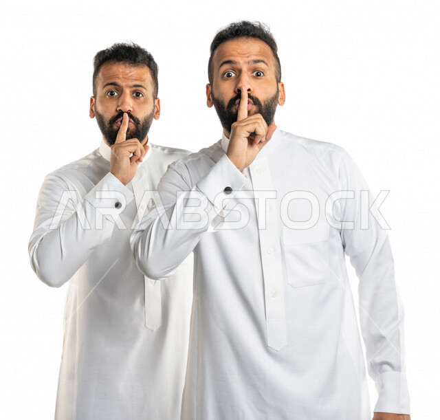 بورتريه لرجلان توأم عربيان خليجيان سعوديان يضعان اصبع السبابة على افواههم ، ايماءات الوجه واليدين تدل على طلب السكوت والصمت ، التوقف عن الكلام ، خفض الصوت ،التهديد، الهدوء والسكون 