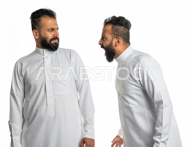 بورتريه لرجلان توأم عربيان خليجيان سعوديان يقفان مقابل بعضهم ، الغضب والقاء اللوم ، النقاش والمواجهة ، التعصب والتوتر ، اساءة الظن ، نقاش حاد ، خلفية بيضاء