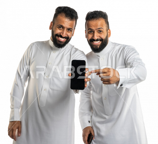بورتريه لرجلان توأم عربيان خليجيان سعوديان يعرضان الهاتف المحمول ببهجة وحماس ، استخدام البرامج والتطبيقات الالكترونية ، الاعلان والترويج، عرض صفحات الويب ، التسويق الالكتروني