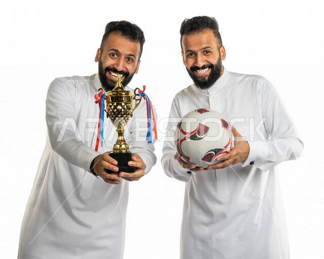 بورتريه لرجلان توأم عربيان خليجيان سعوديان احدهم يحمل كرة القدم والاخر يحمل كأس البطولة ، الفوز و الانتصار في البطولة ، فريق كرة القدم ، المباريات و الألعاب الرياضية ، خلفية بيضاء