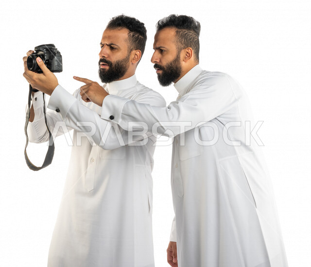 بورتريه لرجلان توأم عربيان خليجيان سعوديان يشاهدان الصور في كاميرا التصوير بايماءات وجه تدل على الاستغراب، صور تذكارية ، التصوير الفوتوغرافي ، هواية و فنون التصوير، توثيق اللحظات السعيدة