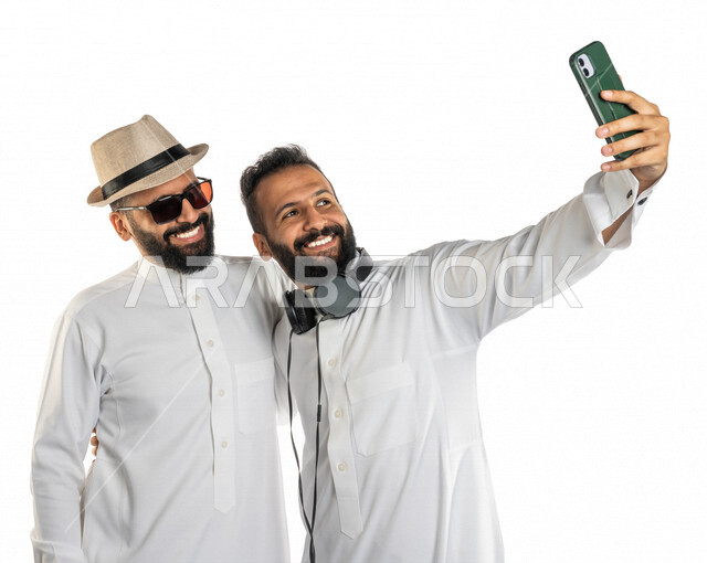 بورتريه لرجلان عربيان خليجيان سعوديان مستمتعان بالتقاط صورة سيلفي من خلال الهاتف المحمول، التقاط صور تذكارية ، صورة جماعية ، توثيق اللحظات السعيدة، اجراء مكالمة فيديو ، بث مباشر ،سياحة وسفر