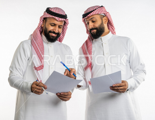 بورتريه لرجلان توأم عربيان خليجيان سعوديان، مناقشة عمل، اجتماع زملاء العمل في مقر عملهم، تطوير العمل وحل المشكلات، توزيع مهام العمل، الوحده والعمل الجماعي، تطوير أهداف الشركة، اتفاقية عمل، بيئة عمل سعودية، خلفية بيضاء