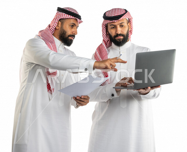 بورتريه لرجلان توأم عربيان خليجيان سعوديان يتنقاشان في مهام العمل، اجتماع زملاء العمل في مقر عملهم، استخدام الحاسوب المحمول في تطوير العمل وحل المشكلات، توزيع مهام العمل، الوحده والعمل الجماعي، بيئة عمل سعودية، استخدام تقنيات حديثة، خلفية بيضاء