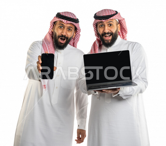 بورتريه لرجلان توأم عربيان خليجيان سعوديان احدهم يحمل الهاتف المحمول والأخر يحمل الحاسوب المحمول، شاشة سوداء مفرغة، البرامج والتطبيقات الالكترونية، الاعلان والترويج، عرض صفحات الويب، التسويق الالكتروني، ايماءات وجه تدل على السعادة والدهشة، خلفية بيضاء