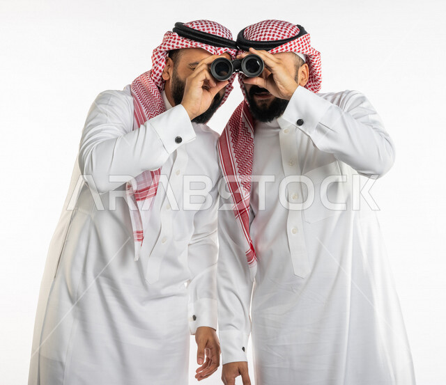 بورتريه لرجلان توأم عربيان خليجيان سعوديان ينظران من خلال منظار الرؤية، الاستكشاف والمغامرة، فريق الكشافة، رؤية مستقبلية، التخطيط المستقبلي، رؤية الاشياء البعيدة ، خلفية بيضاء