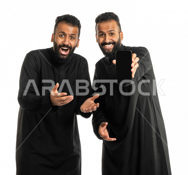 Portrait of two Saudi Arabian Gulf twin men, interconnected brotherly relations, family and social relations, acquaintance and friendships, enthusiastic brothers, facial and hands gestures indicating happiness and enthusiasm, white background