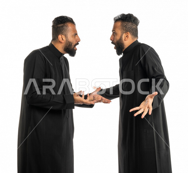 بورتريه لرجلان توأم عربيان خليجيان سعوديان يقفان مقابل بعضهم، نقاش حاد بين اخوين توأم، الغضب والقاء اللوم، النقاش والمواجهة، السؤال والاستفسار عن شيء ما، التهيج والتوتر، الضغط العصبي، ايماءات وجه ويدين تدل على الغضب، خلفية بيضاء