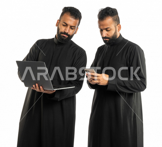بورتريه لرجلان توأم عربيان خليجيان سعوديان، اجتماع زملاء عمل في مقر عملهم، استخدام الحاسوب المحمول في تطوير العمل وحل المشكلات، استخدام الهاتف المحمول، توزيع مهام العمل، الوحده والعمل الجماعي، بيئة عمل سعودية، استخدام تقنيات حديثة، خلفية بيضاء