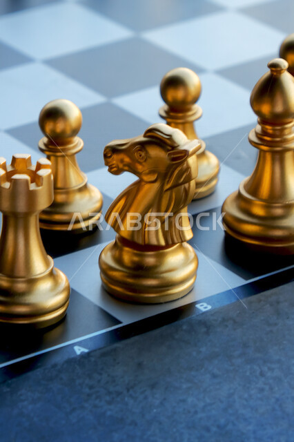 صورة مقربة لأحجار شطرنج ذهبية اللون على طاولة سوداء , لعبة التركيز والتحدي , التسلية والترفيه , مفهوم التخطيط واختيار الاستراتيجيات الصحيحة . 