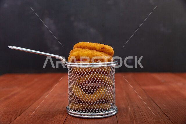 صورة لحلقات البصل المقلية داخل سلة ستانلس صغيرة ، مقبلات لذيذة ، تقديم الطعام ، وجبات سريعة ،  مأكولات ومطاعم 