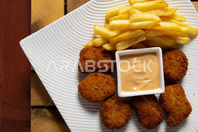 صورة لقطع الدجاج المقلي المقرمش مع صوص الثوم والبطاطس ، دجاج سنيتشل الشهي ، تقديم الوجبات الشهية ، ماكولات ومطاعم عربية