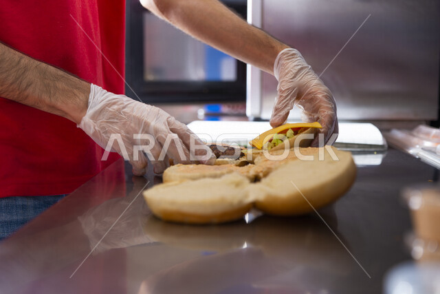 صورة لشيف يقوم بتحضير ساندوتشات البرجر في احد المطاعم ، اعداد وتحضير الوجبات الشهية ، تقديم الوجبات السريعة ، وجبة الهمبرجر اللذيذة ، مطاعم ومأكولات