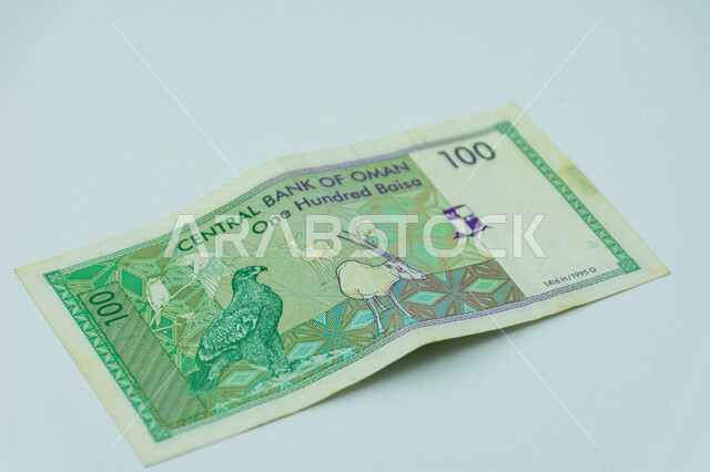 صورة من الخلف لورقة نقدية من فئة 100 بيسة عمانية، صورة الصقر والمها العربي، عملة ورقية، مالية واقتصاد، البنك المركزي العماني، العملة الرسمية لسلطنة عمان، خلفية بيضاء