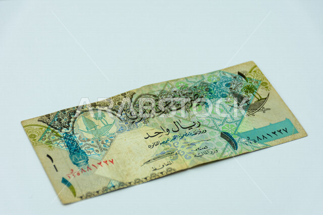 صورة لورقة نقدية من فئة 1 ريال قطري، صورة لشعار دولة قطر مطبوعة على عملة الريال القطري، عملة ورقية، مصرف قطر المركزي، العملة الرسمية لدولة قطر، خلفية بيضاء