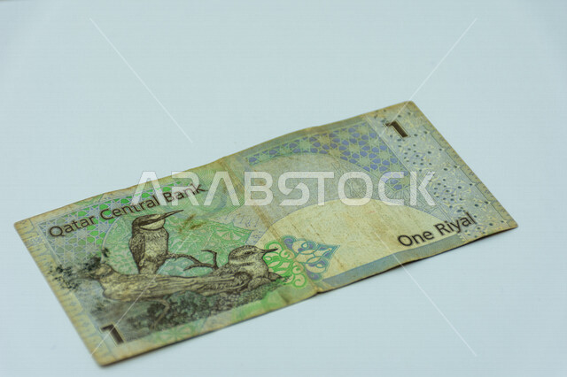 صورة من الخلف لورقة نقدية من فئة 1 ريال قطري، صورة لثلاثة طيور مطبوعة على عملة الريال القطري، عملة ورقية، مصرف قطر المركزي، العملة الرسمية لدولة قطر، خلفية بيضاء