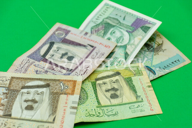 صورة لمجموعة أوراق نقدية خليجية، الريال السعودي، الريال القطري، البيسة العمانية، خادم الحرمين الشريفين، الملك عبد الله بن عبد العزيز، السلطان قابوس بن سعيد، عملات ورقية خليجية، خلفية خضراء