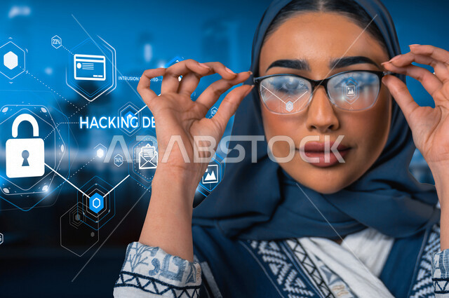 صورة مقربة لمرأة عربية خليجية سعودية، تنظر إلى الكاميرا، إستخدام نظام حماية أمن لمنع الهاكر، أيقونة قفل الأمان بخاصية الهولوجرام ثلاثية الابعاد، الحماية والأمان، الحفاظ على البيانات الشخصية والدخول الآمن