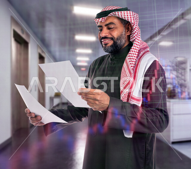 رجل عربي خليجي سعودي في مقر العمل، يحمل بيده أوراق لمخطط بياني مالي، خلفية لرسومات بيانية إحصائية للبورصة المالية بتقنية الهولوجرام ثلاثية الأبعاد، الاستثمار المالي والاقتصادي، دراسة السوق، متابعة الأسهم المالية للمشاريع التطويرية