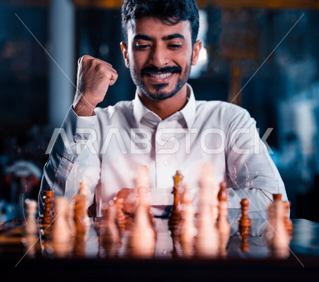 صورة مقربة لشاب عربي سعودي خليجي يلعب لعبة الشطرنج، مفهوم التركيز والتحدي، التخطيط والتفكير، لعبة رقمية استراتيجية على رقعة الشطرنج، إيماءات تدل على الفوز، أنشطة ترفيهية، قضاء أوقات ممتعة في اللعب، تسليه وترفيه