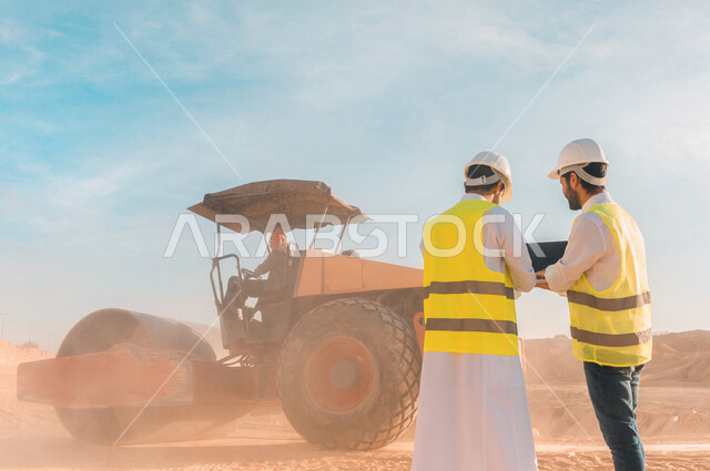 مهندسان معماريان سعوديان خليجيان يناقشان مخطط لمشروع البناء، إرتداء سترة الحماية الخاصة بالعمل، الإشراف والنقاش لمشاريع قيد الانشاء، مفهوم الهندسة المعمارية، متابعة العمل والإشراف على المشاريع، إعطاء أوامر خاصة بالعمل، مهن ووظائف هندسية، ادارة المشاريع