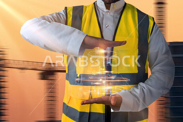 رجل عربي خليجي سعودي، مهندس معماري يرتدي سترة الحماية الخاصة بالعمل، مهندس يحمل شيء بين يديه، امساك واحتواء عنصر هلوجرامي، مشروع هندسي مبتكر، خلفية لرافعات البناء مدموجة بمخطط شبكي بتقنية الهولوجرام
