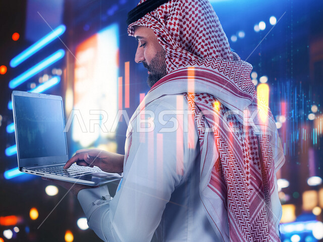 رجل أعمال عربي سعودي خليجي يستخدم جهاز الابتوب، رسوم بيانية إحصائية للبورصة المالية بتقنية الهولوجرام ثلاثية الأبعاد، تطوير الشركات والمشاريع الاقتصادية، التجاره الإلكترونيه، متابعة الأسهم، الإستثمار المالي